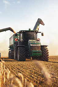 A tractor with trailer being filled by a combine harvester.